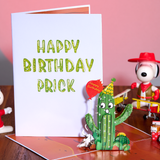 Birthday card with cactus decoration and 'Happy Birthday Prick' text, Snoopy in background