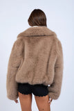 Person wearing a fluffy brown jacket on a white background